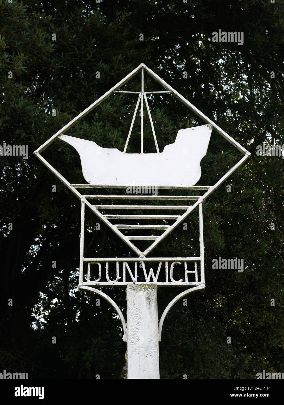 A metal sign with a ship motif for the village of Dunwick Suffolk UK white against a dark background Stock Photo