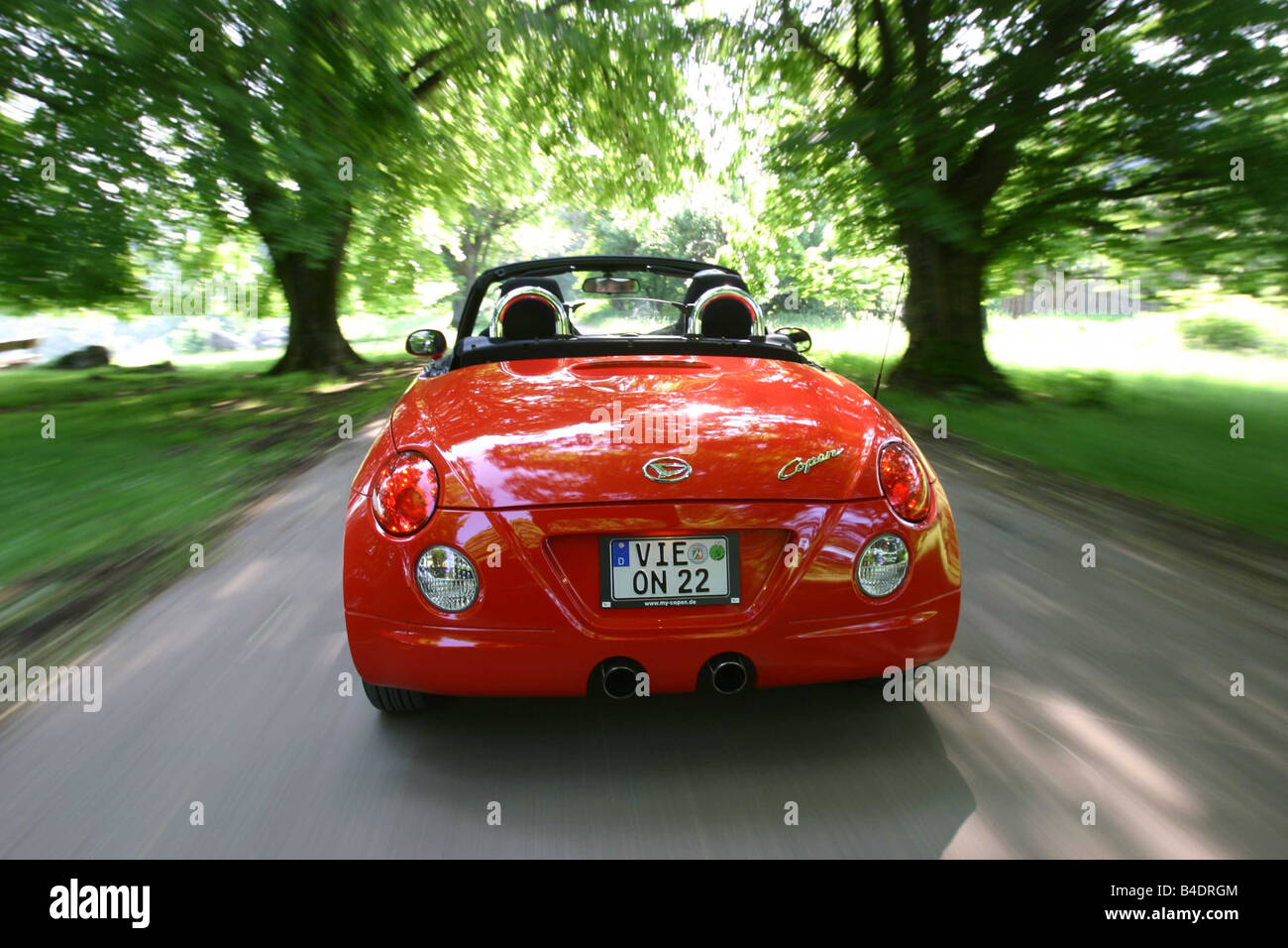 Car, Daihatsu Copen, Convertible, model year 2003-, red-orange , open top, driving, country road, diagonal from the back, Rear v Stock Photo