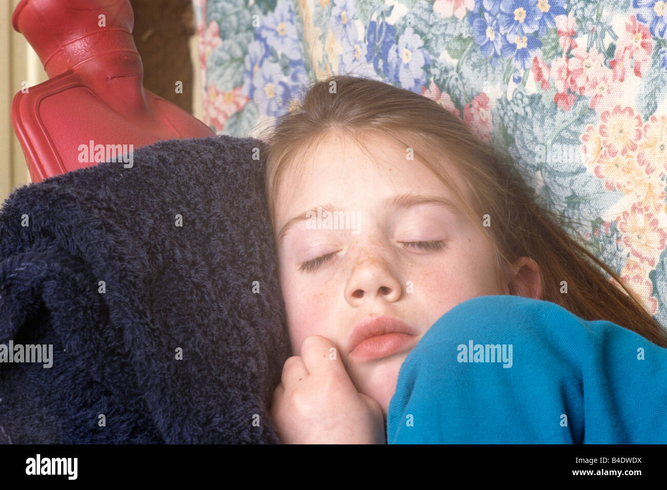 little girl with earache curled up with a hot water bottle against her