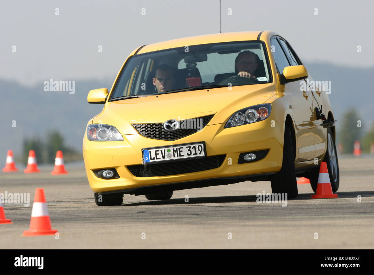 Car, Mazda 3 Sport 1.6, Lower middle-sized class, Limousine, model year 2003-, FGHDS, yellow, driving, diagonal from the front, Stock Photo