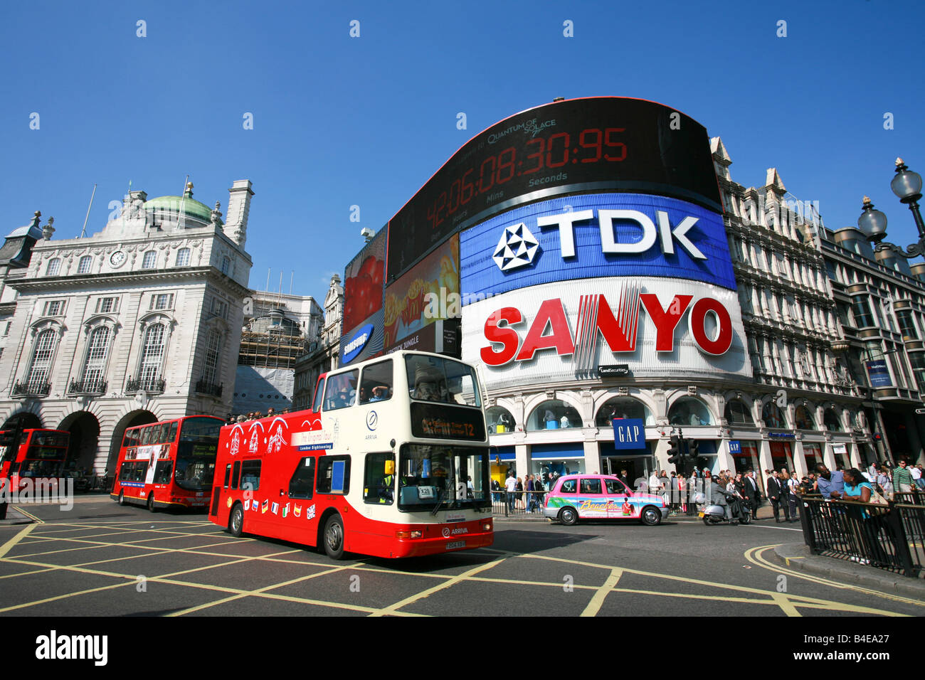 Red open top London double decker sightseeing tourist bus passes in front of famous neon signs in Piccadilly Circus London UK Stock Photo