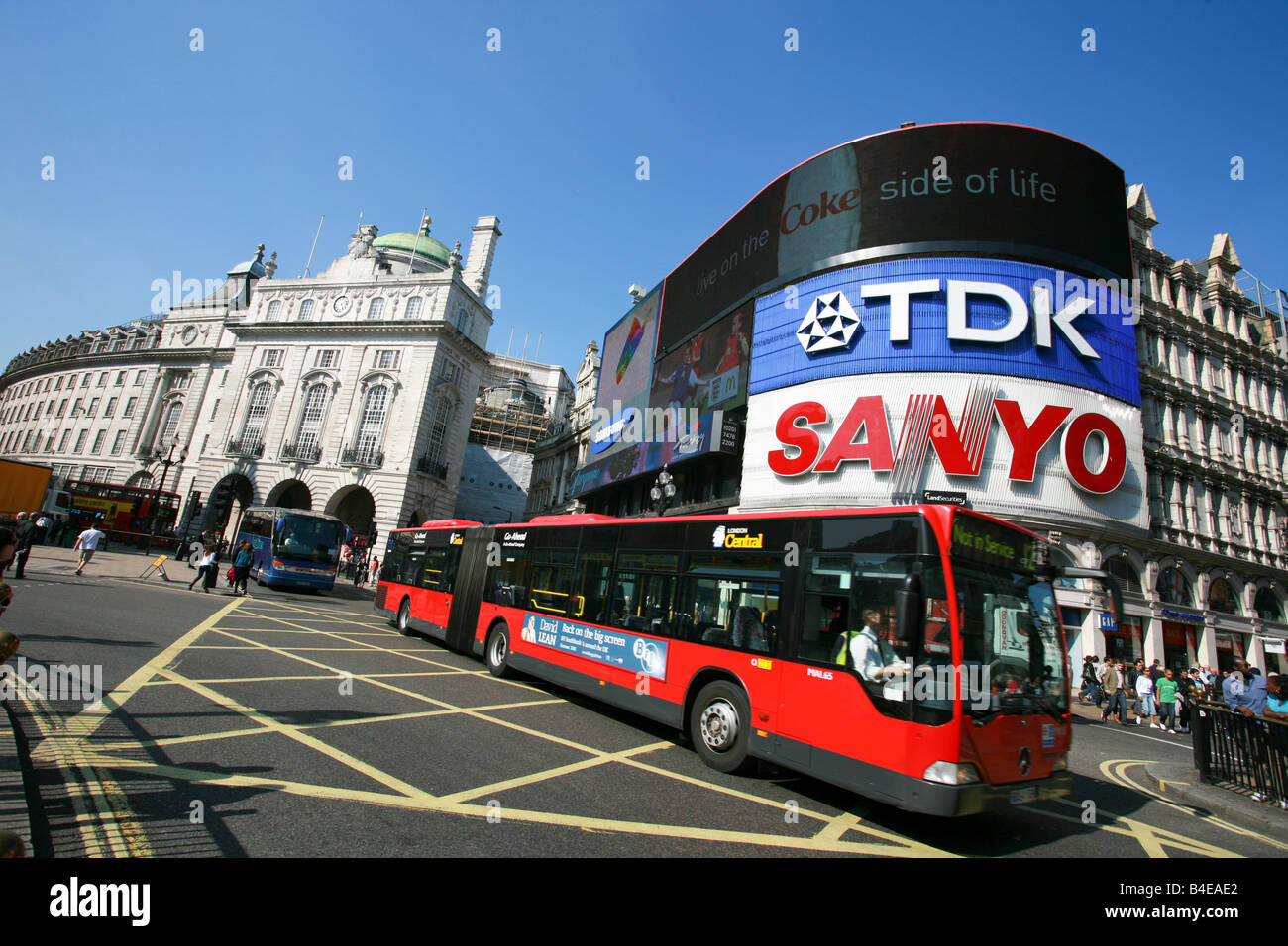Red London double length bendy bus passes in front of famous neon signs in Piccadilly Circus London major tourist landmark UK Stock Photo