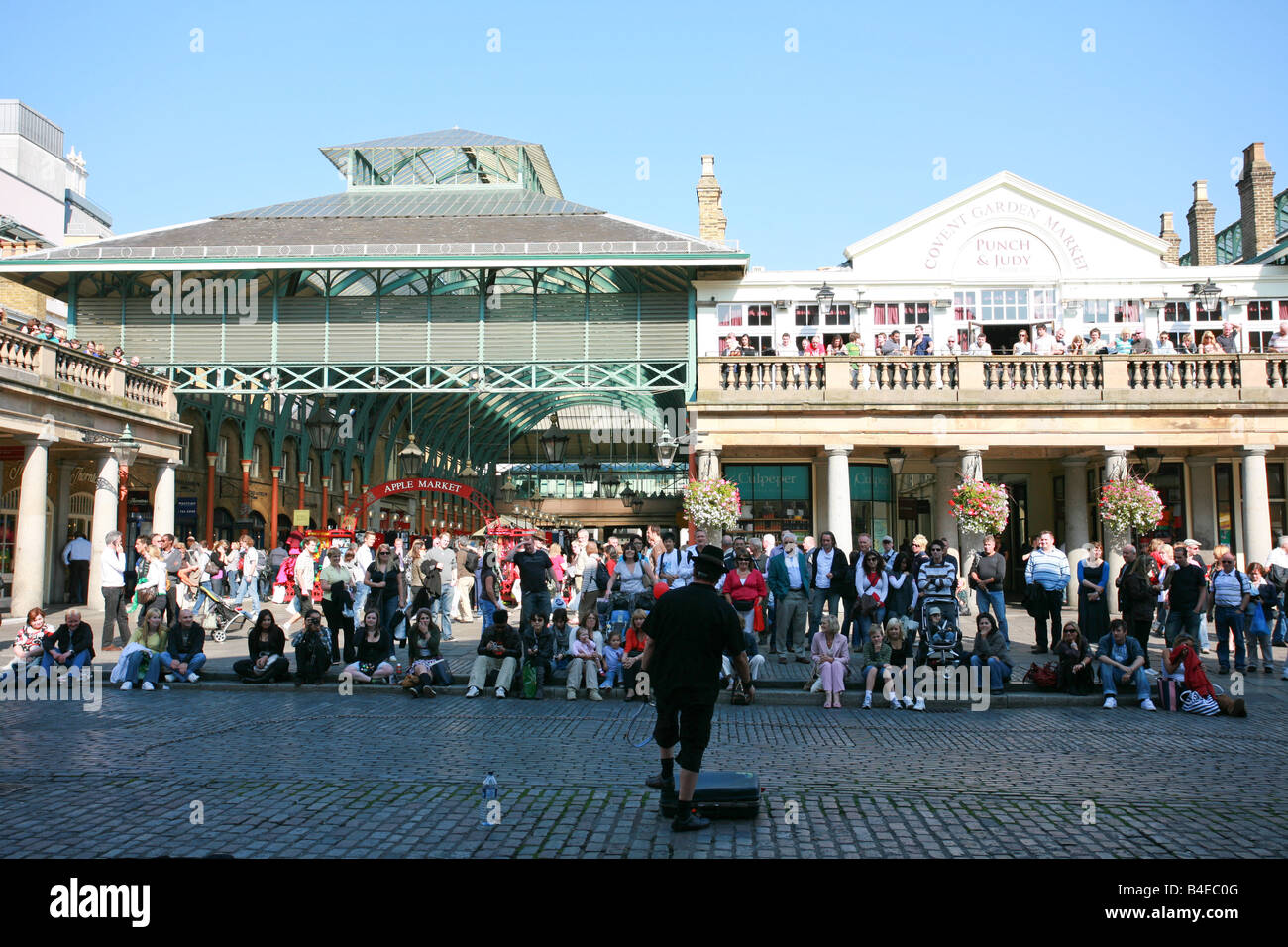 Street performer plays to a large crowd of tourists assembled outside Covent Garden, a popular sightseeing location in London UK Stock Photo