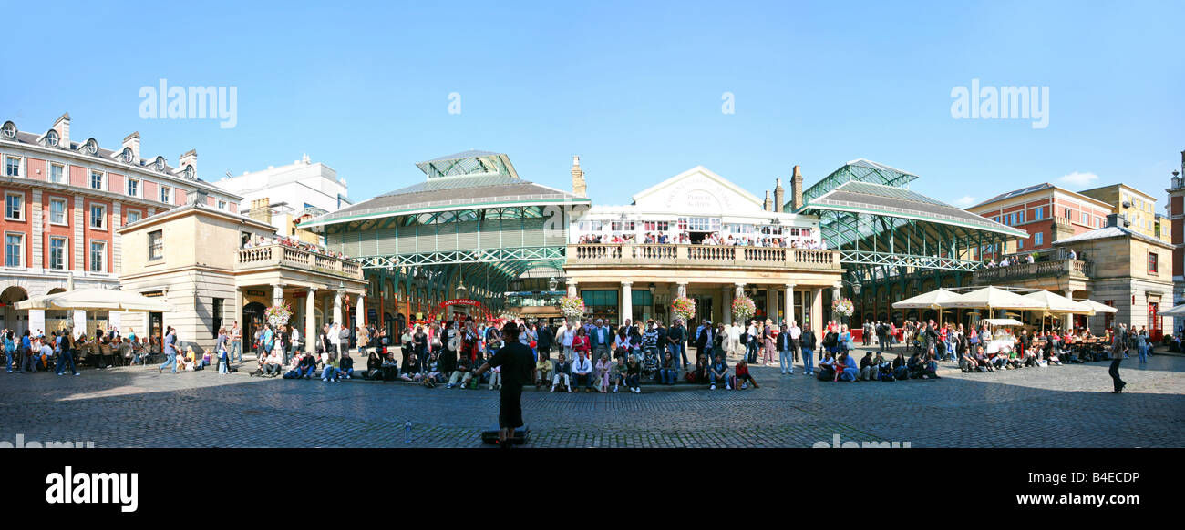 Street performer plays to a large crowd of tourists assembled outside Covent Garden, a popular sightseeing location in London UK Stock Photo