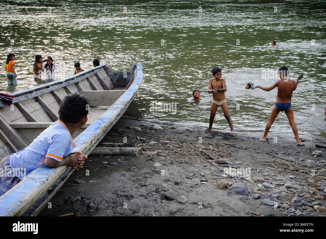 Playing children throw mud at each other on the banks of a river in