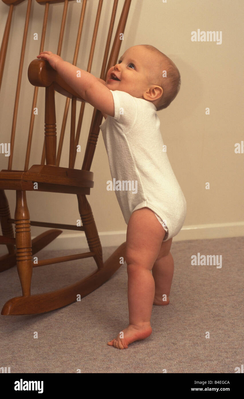 baby holding on to a chair to pull himself up Stock Photo Alamy