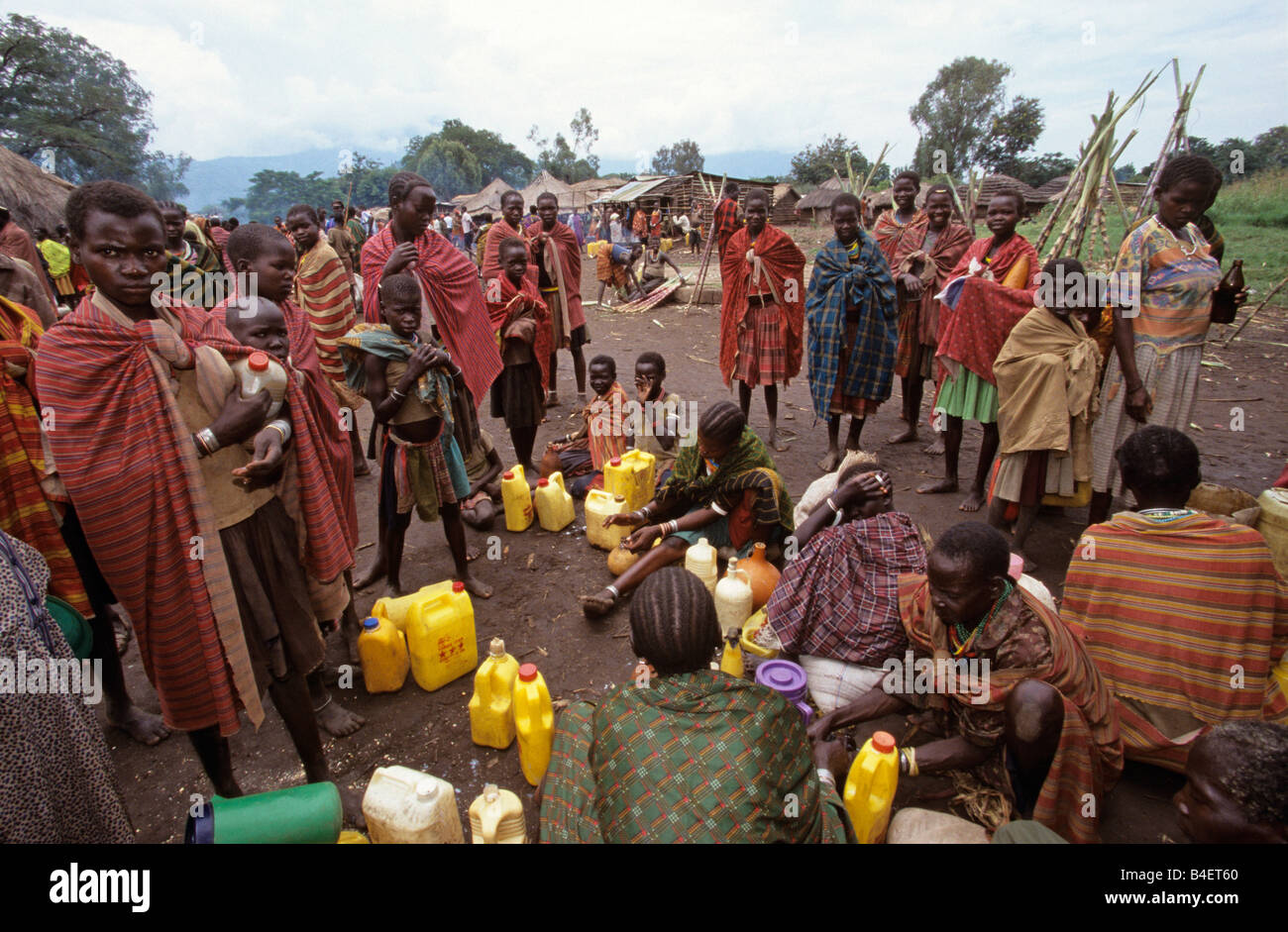 Ethnic Karamojong villagers waiting with jerrycans in village, Karamoja, Uganda Stock Photo