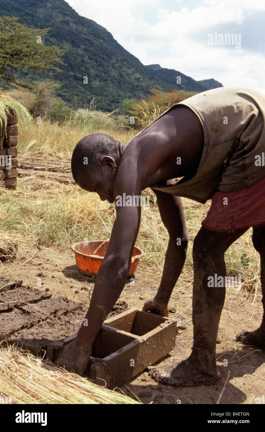 Brick maker using moulds, working on hill. Uganda. Stock Photo