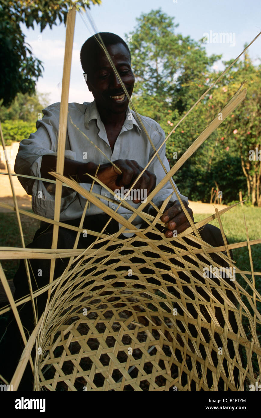 Male basket weaver weaving circular basket, Uganda, Africa Stock Photo