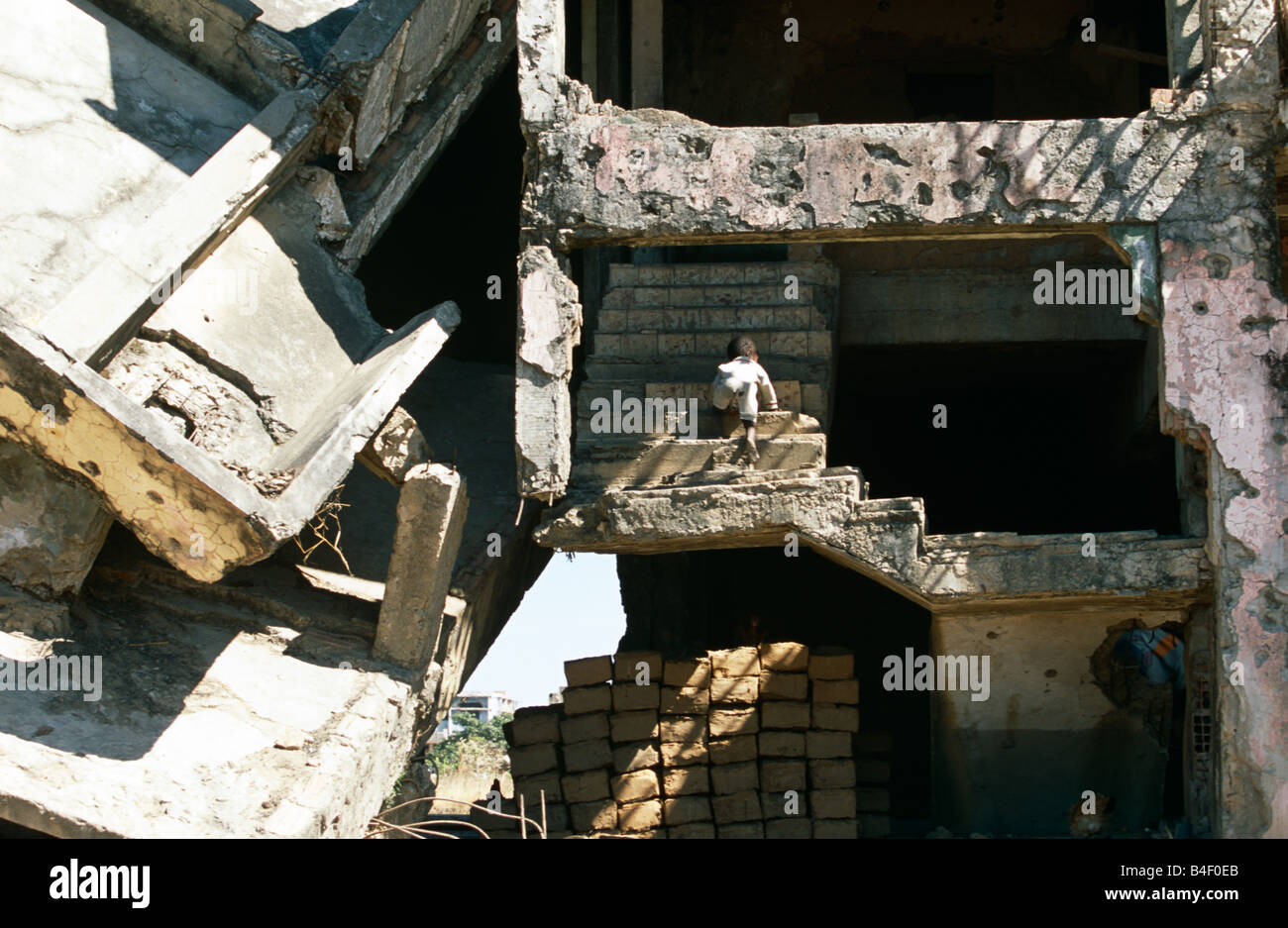 Child climbing up stairs in tumbling building in war-torn Angola Stock Photo