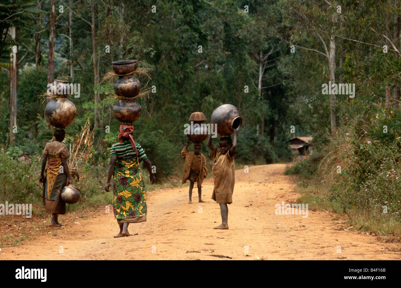 Women and children balancing pots on head, Burundi Stock Photo
