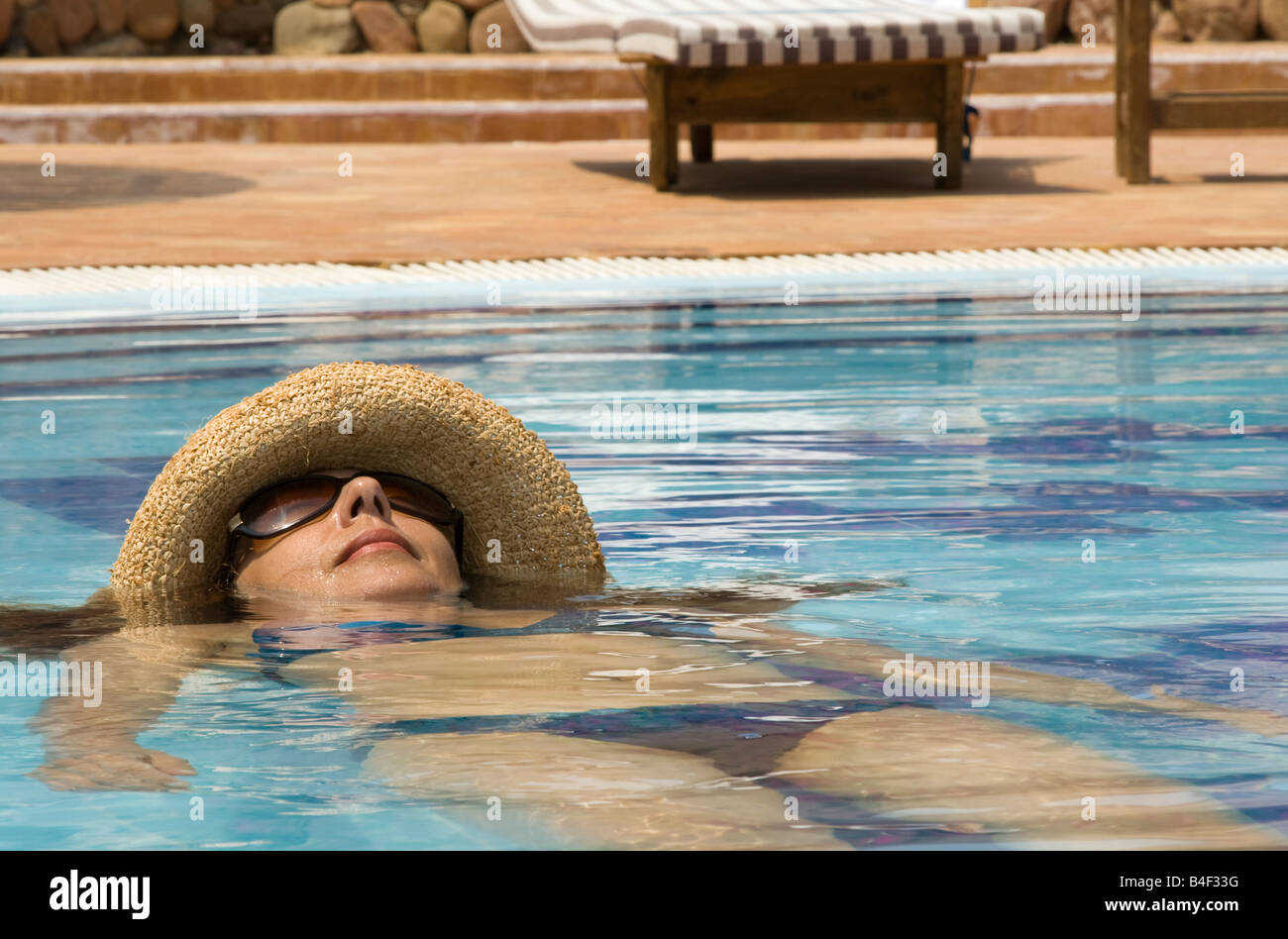 Young woman in swimming pool wearing straw hat Stock Photo - Alamy