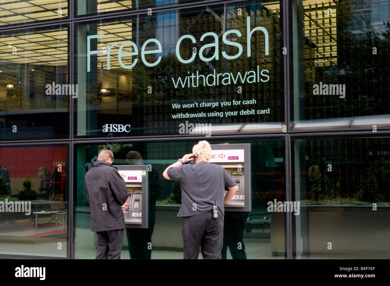 UK- Customers drawing cash at ATM machine outside HSBC HQ in Canary Wharf London Photo Julio Etchart Stock Photo