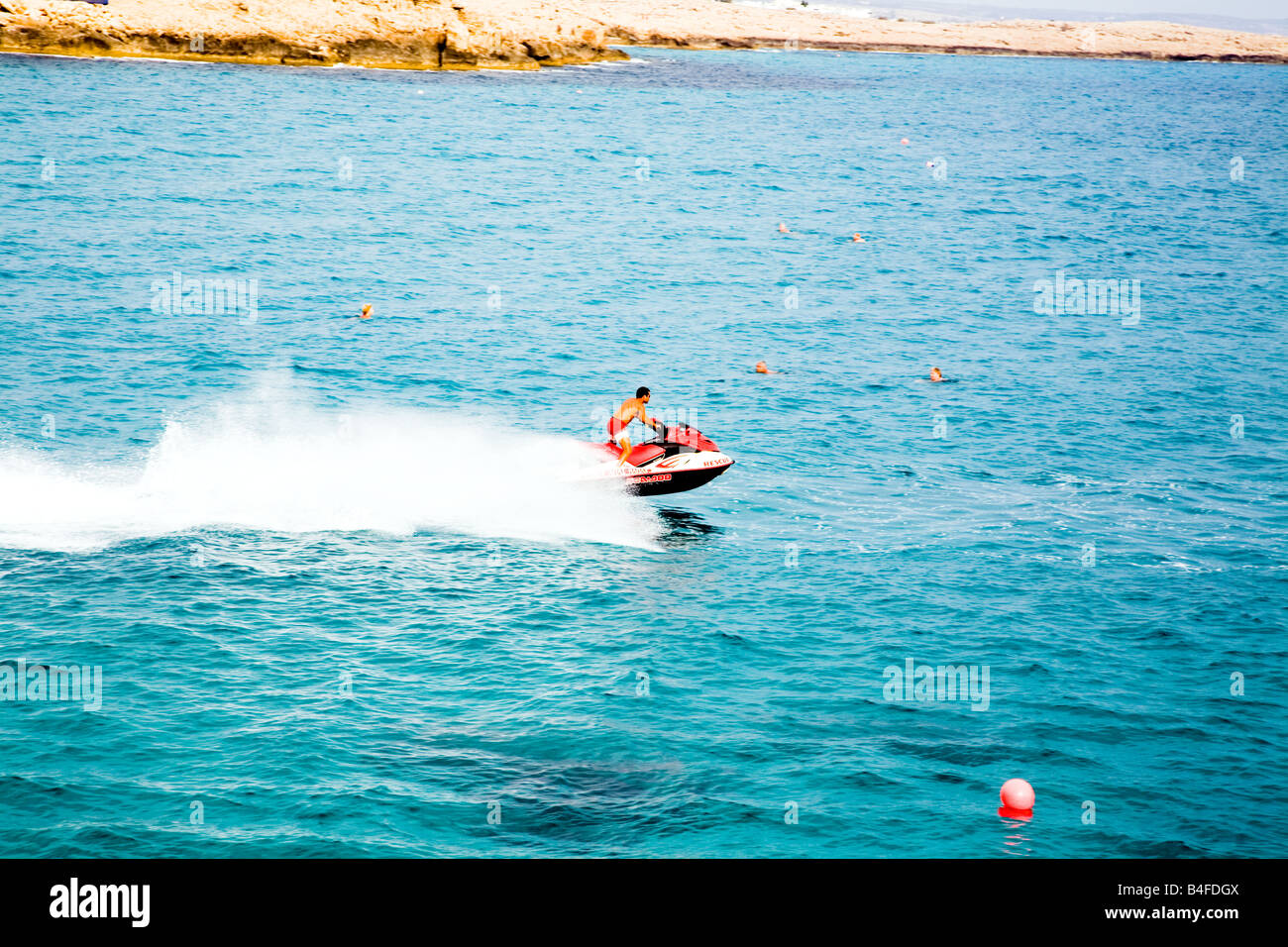 A rescue jet ski patrolling the waters off Nissi beach, Cyprus, with swimmers in the water Stock Photo