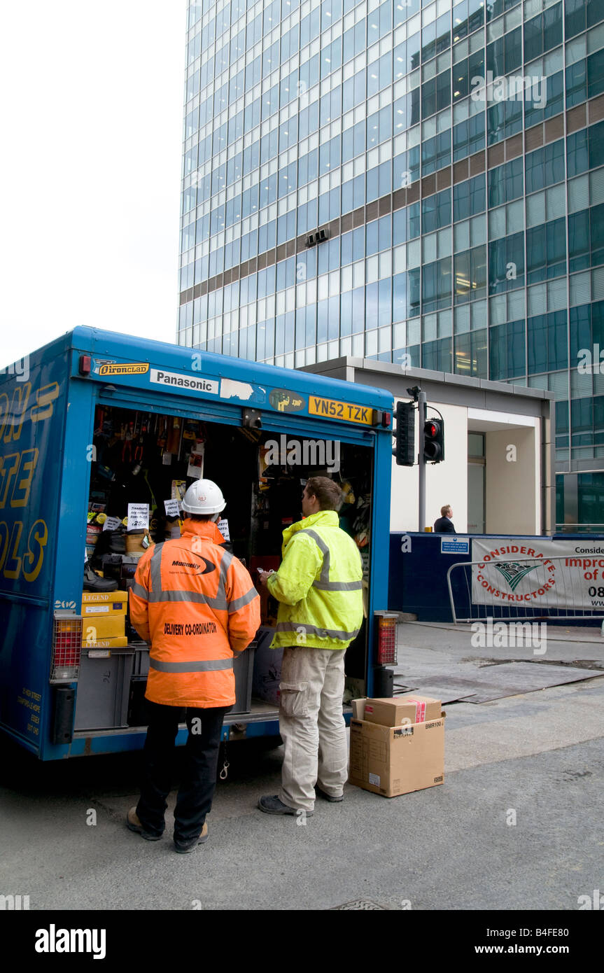 Eastern European migrant building workers buying working gear from ambulant vendor  in Canary Wharf,London Photo Julio Etchart Stock Photo