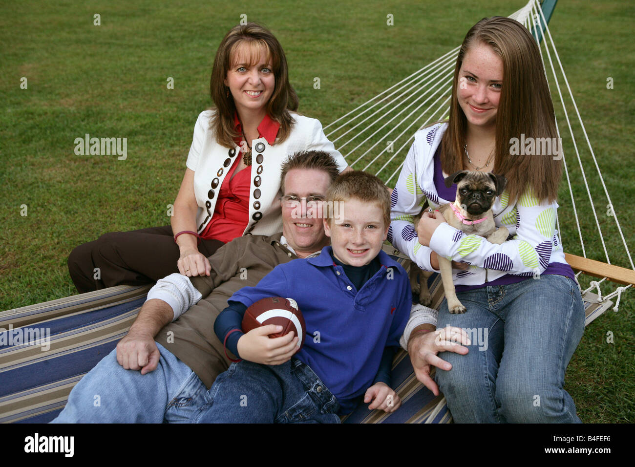 Happy Family with one son and one daughter father and mother in back yard at home with football and pet dog Stock Photo