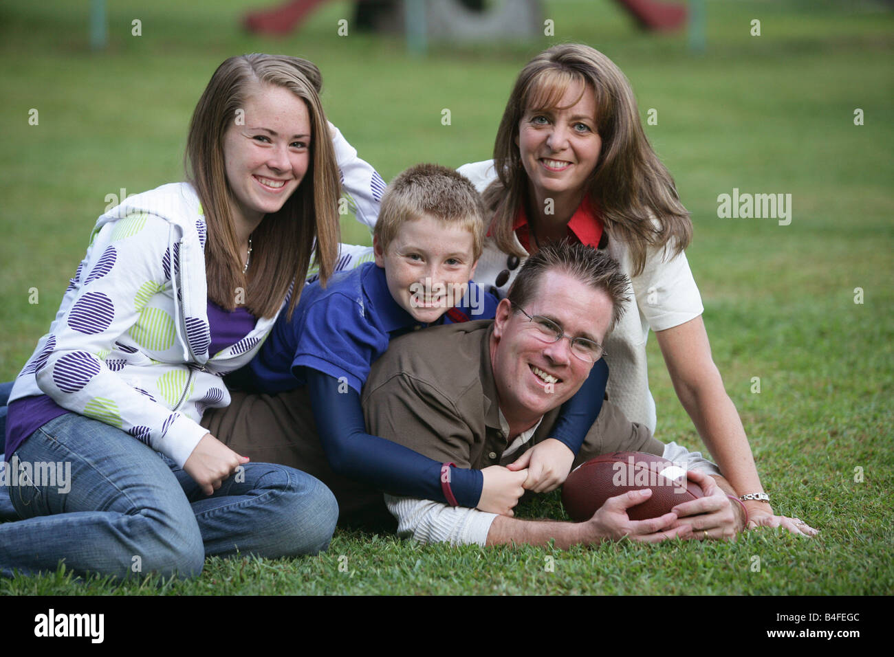 Happy Family with one son and one daughter father and mother in back yard at home with football Stock Photo