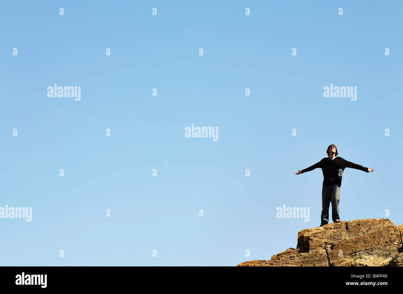 Man Standing On The Edge Of A Cliff With His Arms Outstretched Stock ...