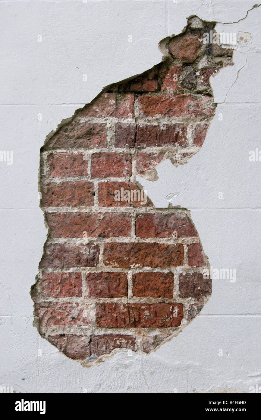 Red brick wall showing through plaster on a house wall Stock Photo Alamy