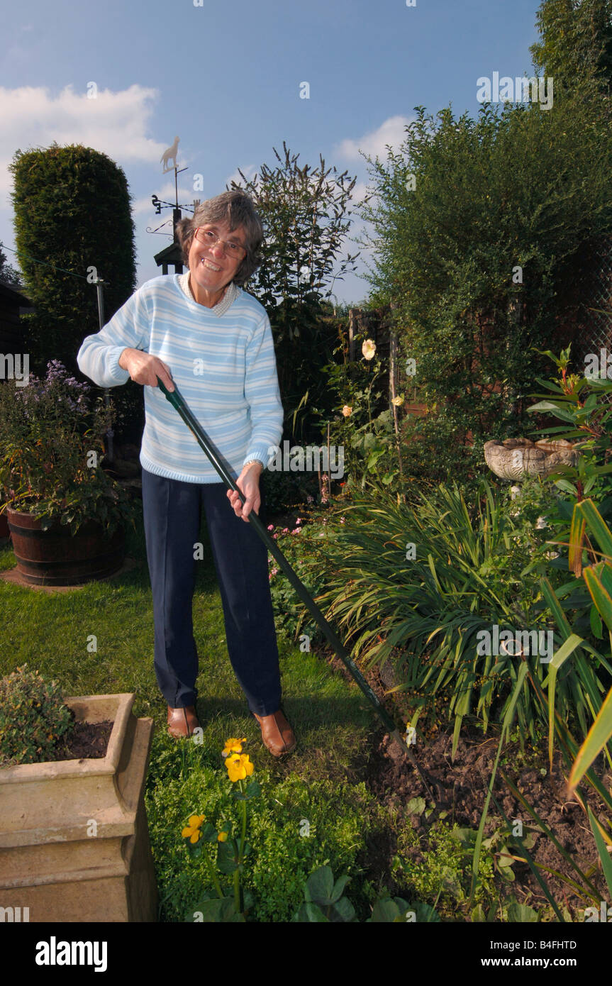 A Woman In Her Seventies Hoeing Her Garden Stock Photo