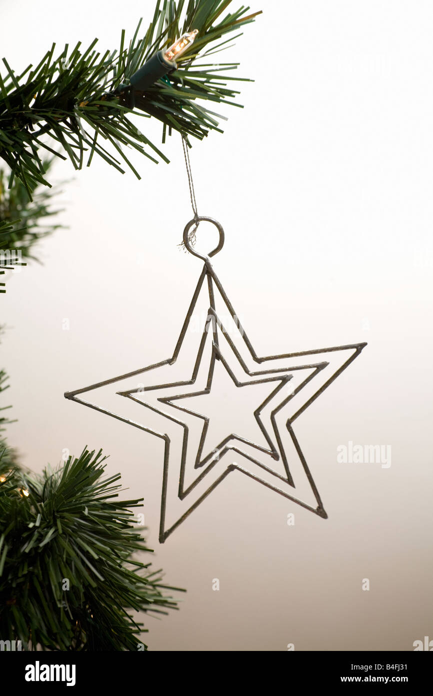 A Xmas star ornament hanging from the tree Stock Photo