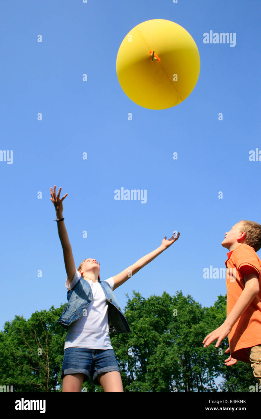 boy and girl playing with a big yellow balloon Stock Photo