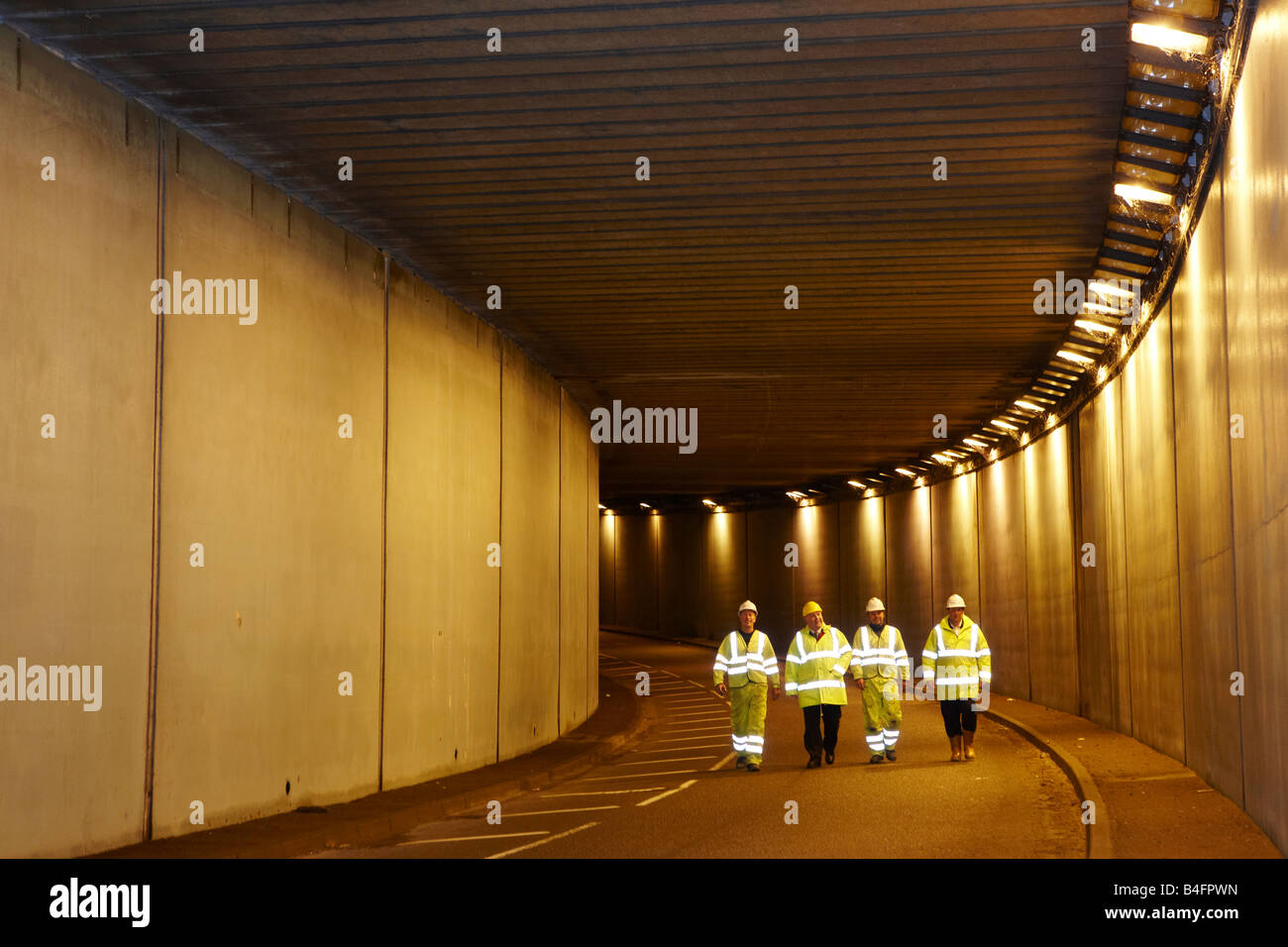 Four 4 engineers walking in road tunnel Stock Photo