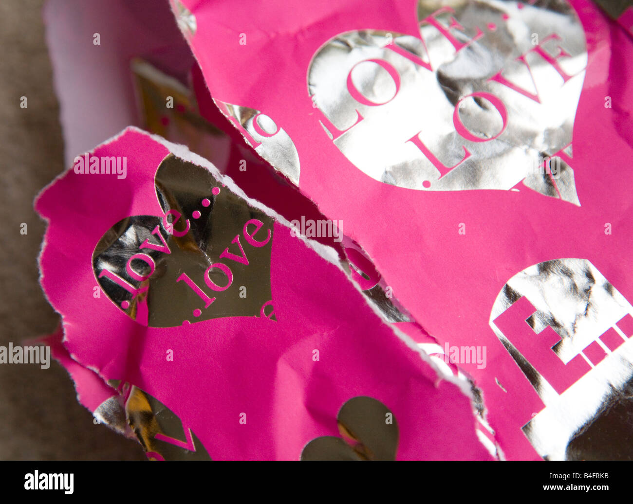 A present. Torn pink wrapping paper with silver hearts. Stock Photo