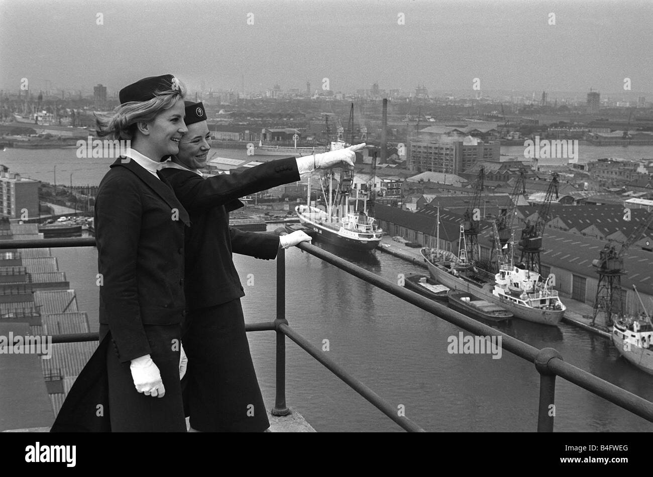 Port of London Dock Guides June 1965 Two of the guides talk as they look over the ships in the docks on the River Thames in London One of the ladies points across the docks Stock Photo