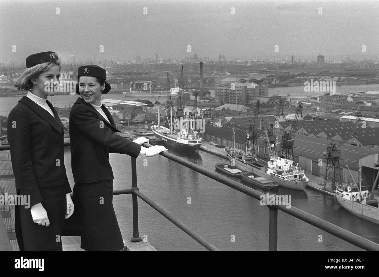Port of London Dock Guides June 1965 Two of the guides talk as they look over the ships in docks on the River Thames in London Stock Photo