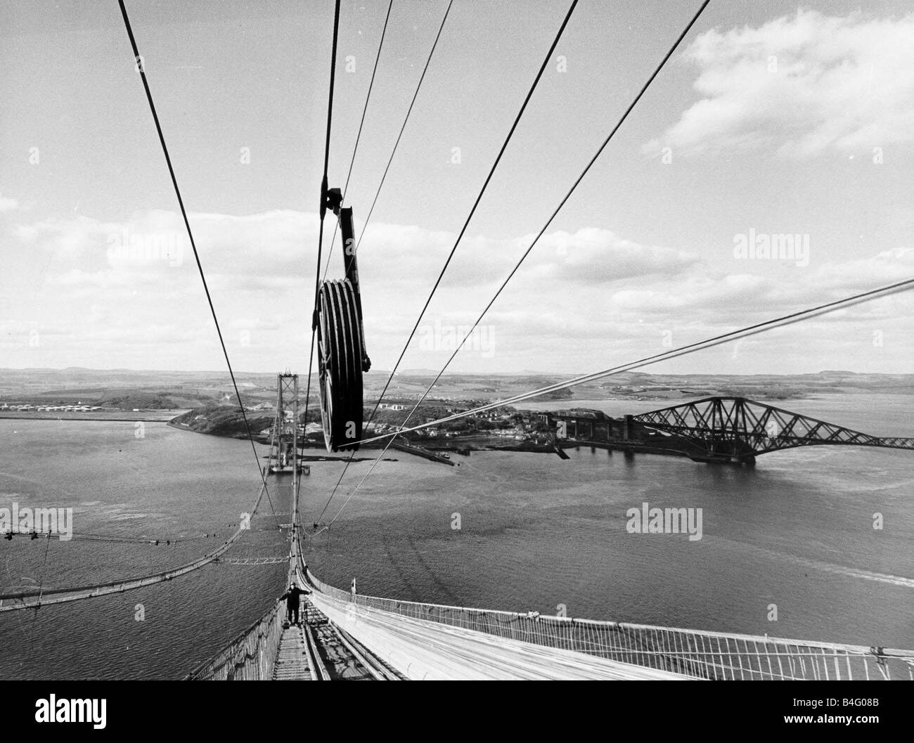 Forth Road Bridge construction June 1962 Wires being strung across the Forth as workman walking on boarding with the Forth Railway Bridge in background Stock Photo