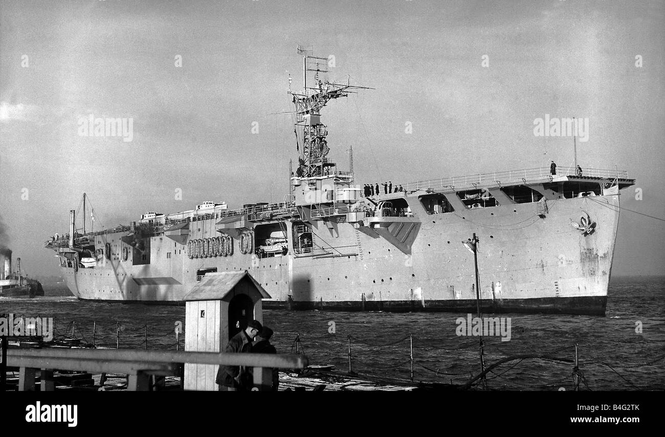 Ships Royal Navy Aircraft Carrier HMS Campania comes in to dock at Portsmouth naval dockyard December 1952 Stock Photo