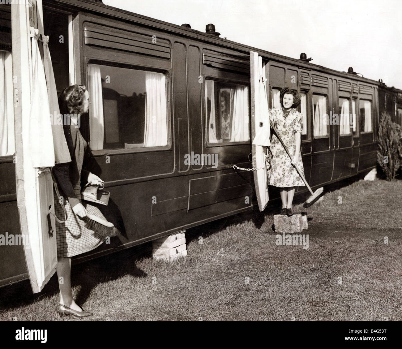 Housing February 1948 Twenty four disused coaches are being converted into mordern all in electric bungalows in the grounds of one of our biggest rail rolling stock engineers at Slough Kathleen Anstee r wearing overall and June Crowhurst try put the new Railway carriage home which are to help in Britains export drive in order Stock Photo