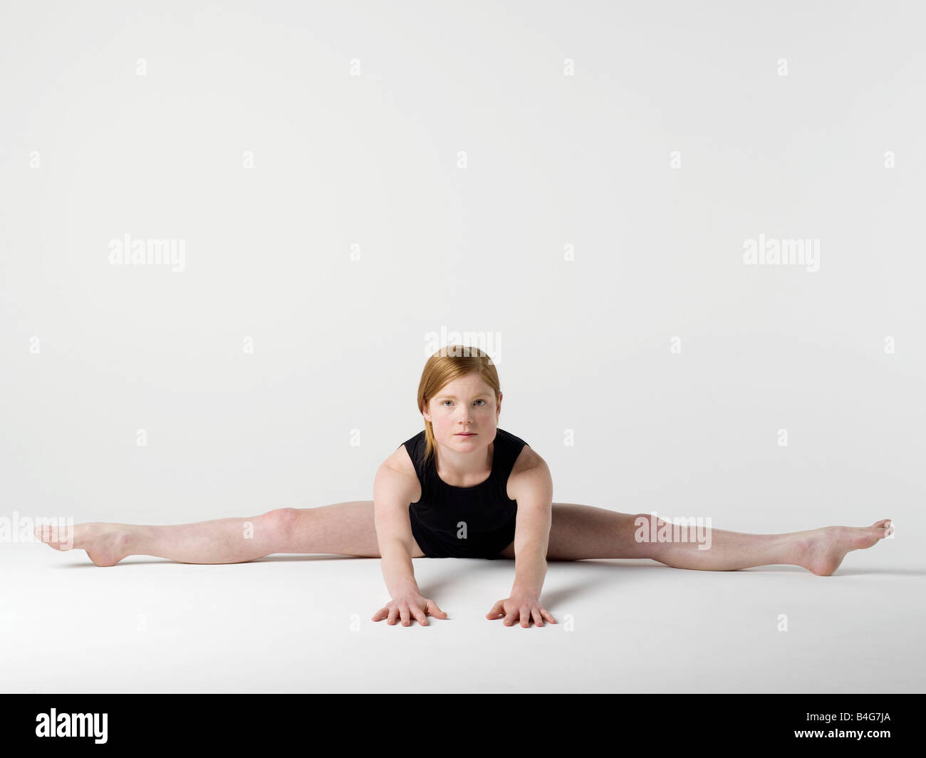 A young woman practicing the 'Spread Leg Forward Fold' yoga pose Stock Photo