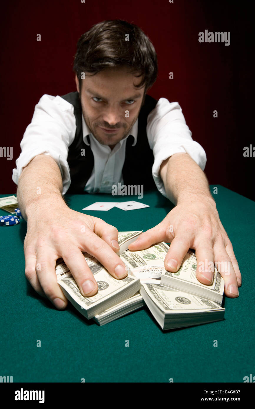 A man at a high stakes poker game pulling a pile of money towards him Stock  Photo - Alamy