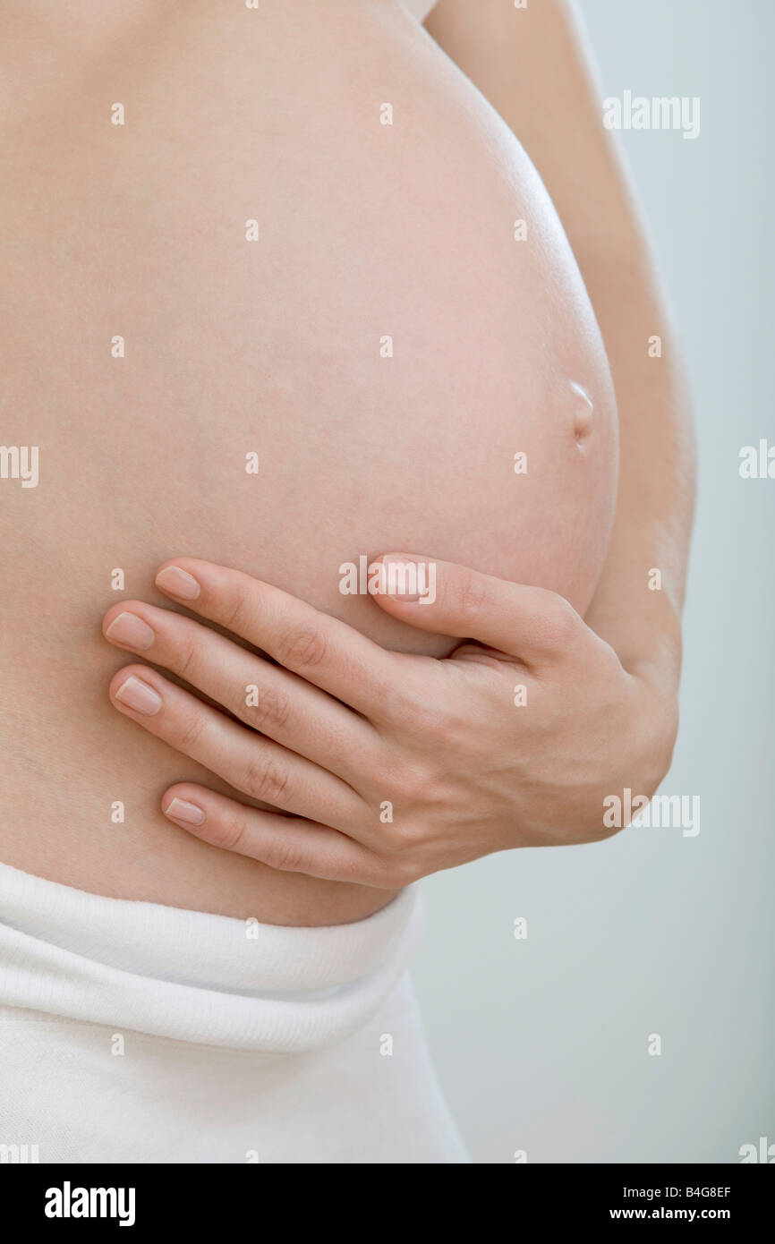 A pregnant woman holding her stomach Stock Photo - Alamy