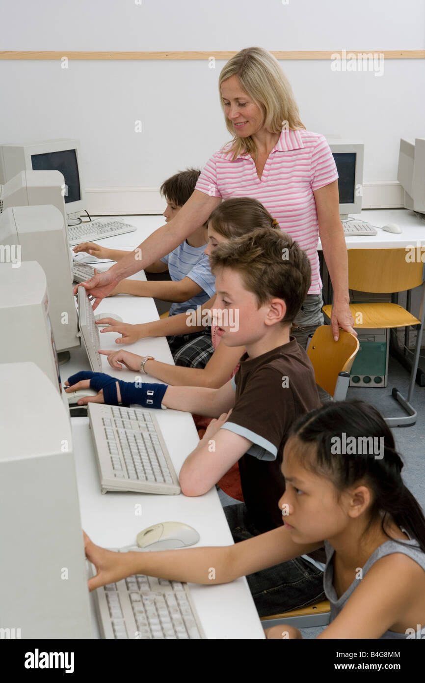 A teacher and four pre-adolescent children in a computer lab Stock ...
