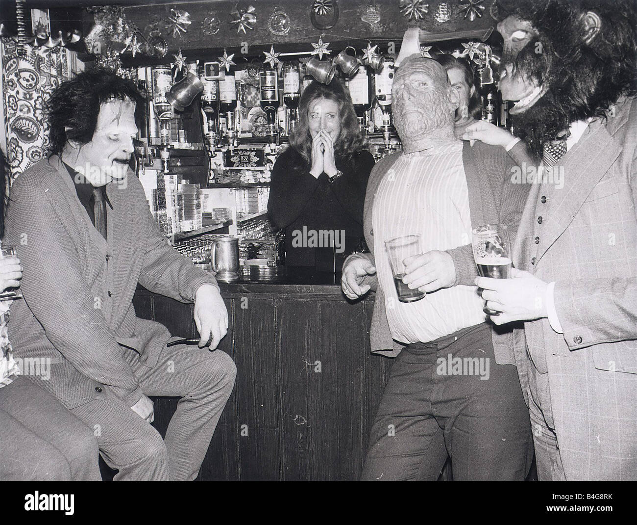 Drinkers standing at the bar of the Red Lion in Kings Langley Hertfordshire wearing masks and hold beer glasses Stock Photo