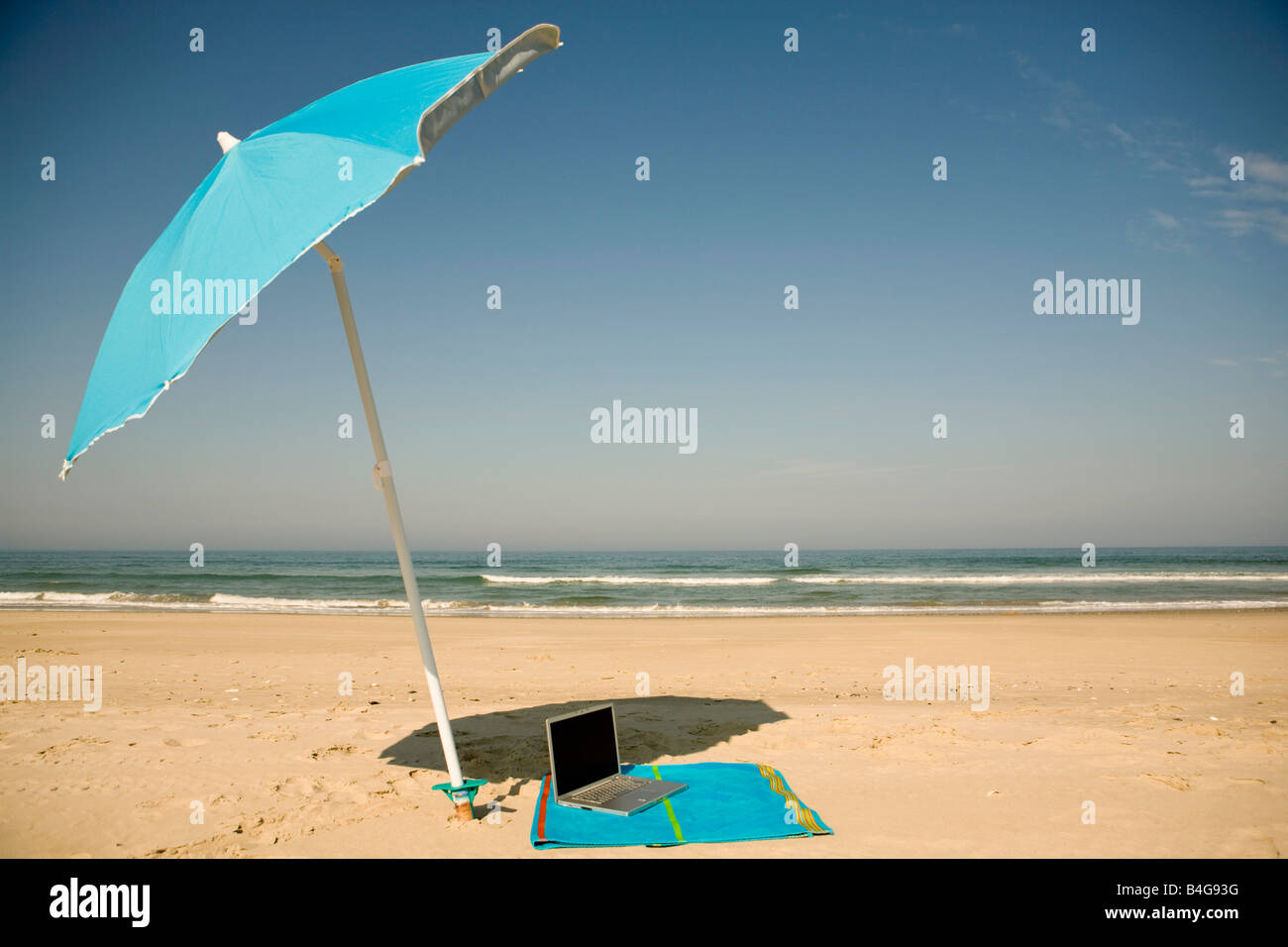 A laptop lying on a beach towel on a beach Stock Photo