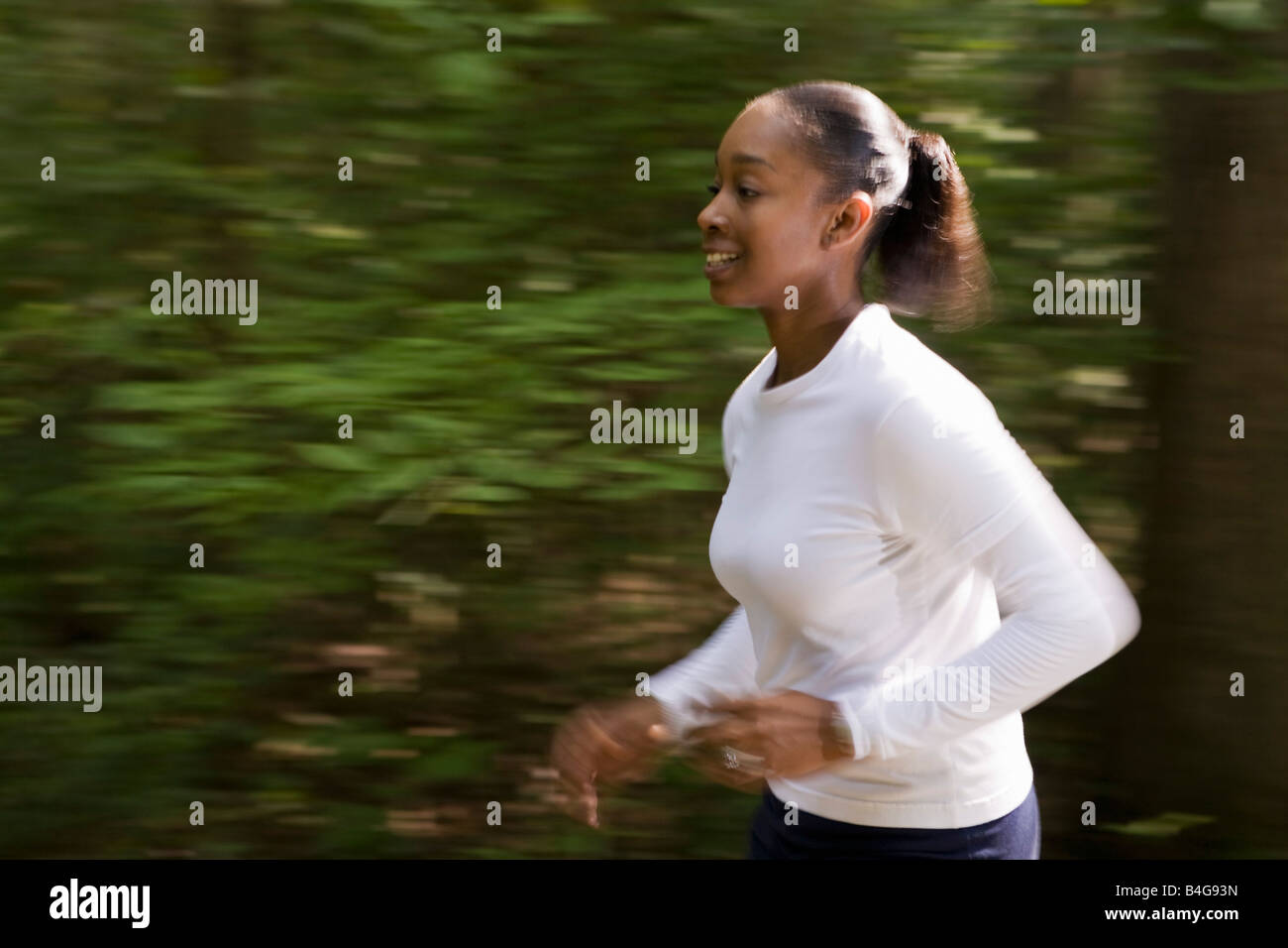 A woman jogging through wooded park Stock Photo