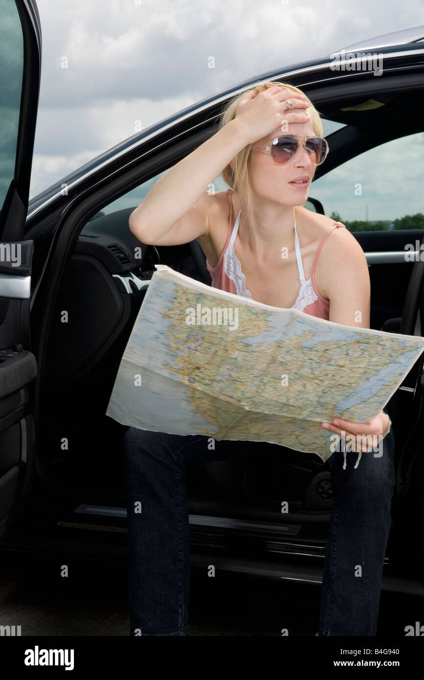 A woman reading a roadmap and looking confused Stock Photo