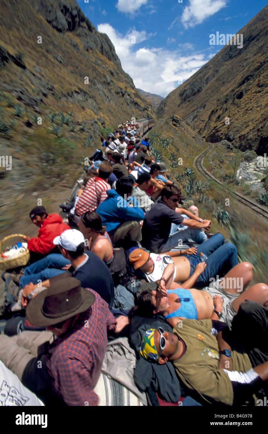 Tourists and locals onboard the Devils Nose Railway train sit on the top of the rail cars travelling through the mountains. Stock Photo