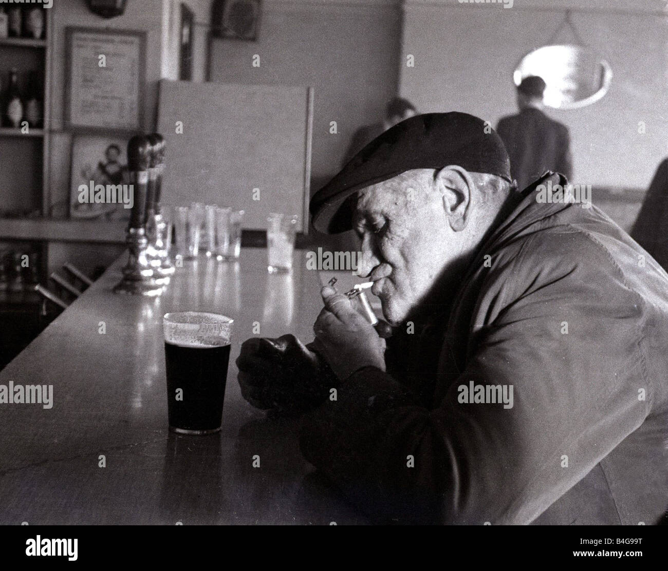 cigarette pub The Chimes Lansbury Public House Pub 1953 A old man sits at the bar with a  pint of beer lighting his cigarette relaxing from the rigors of work Stock  Photo