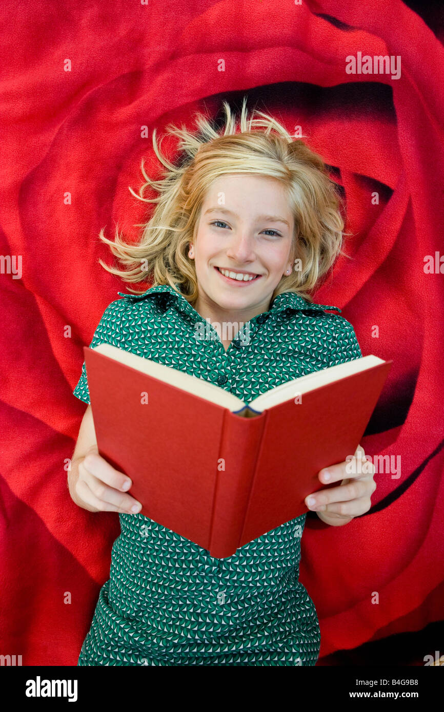 A girl lying on a blanket and reading a book Stock Photo Alamy