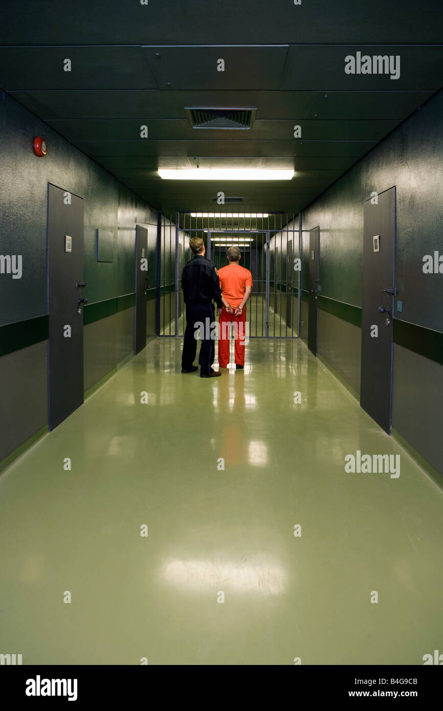 A prison guard leading a prisoner along a corridor Stock Photo