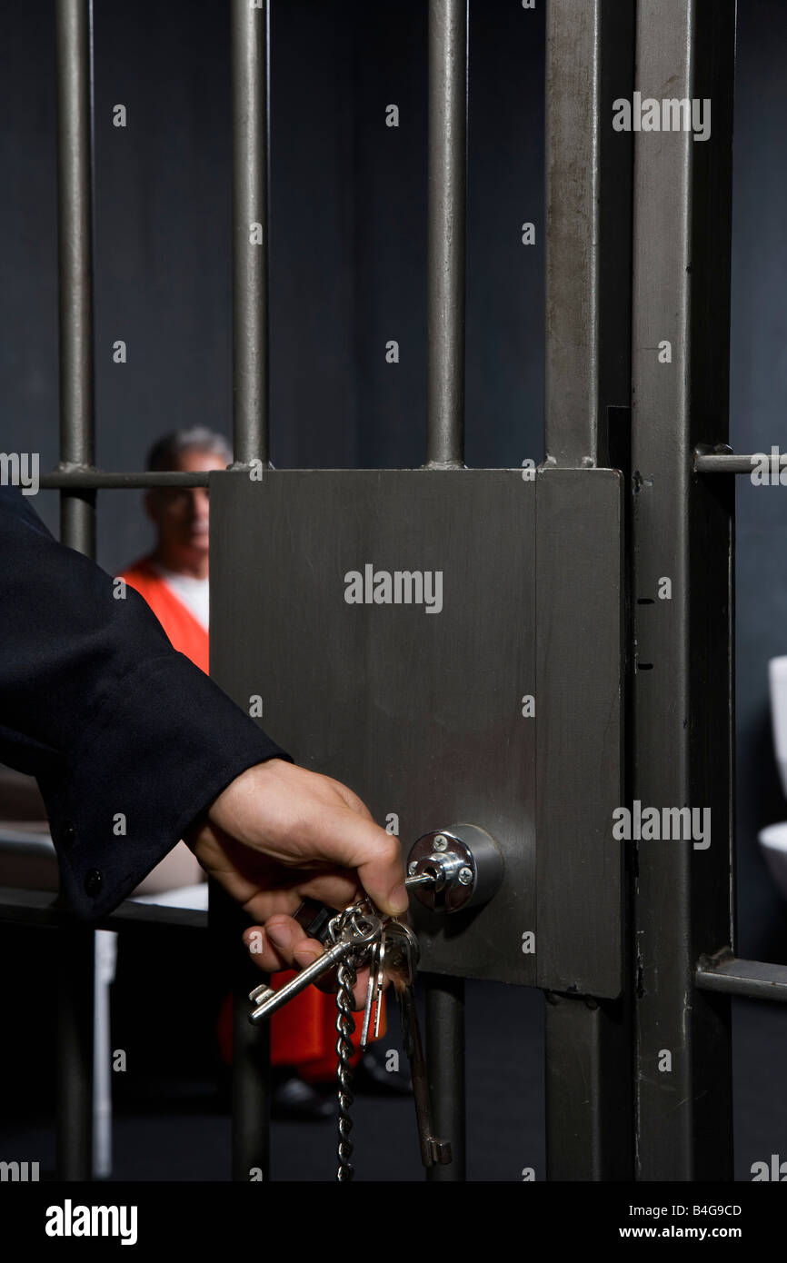 A prison guard locking a prison cell door Stock Photo