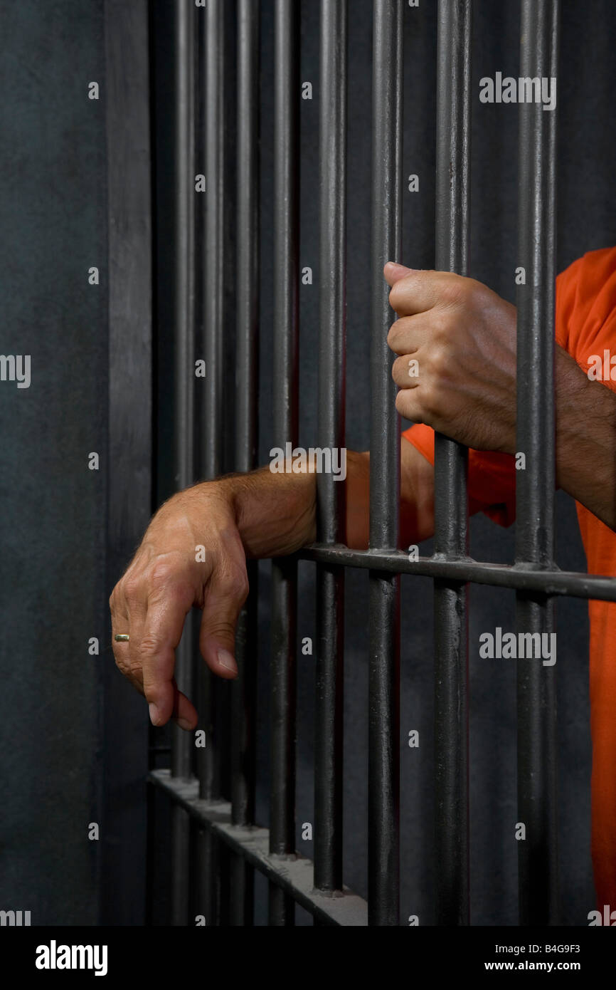 A prisoner standing behind his prison cell bars Stock Photo