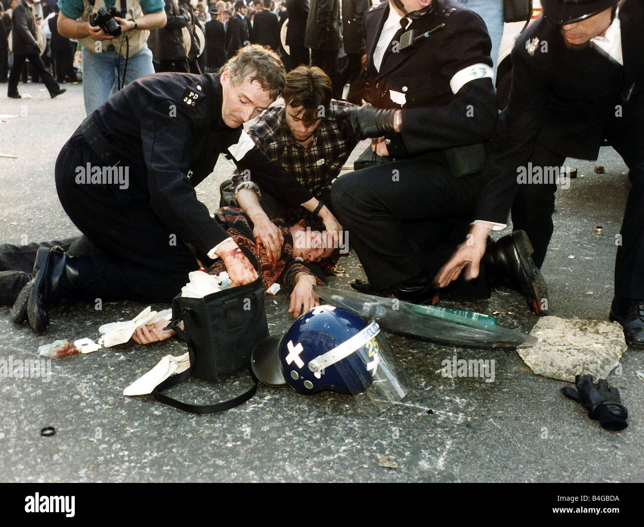 Demonstrations Poll Tax Riots March 1990 A man lies on the ground with a bleeding head wound being attended to by the police in Stock Photo