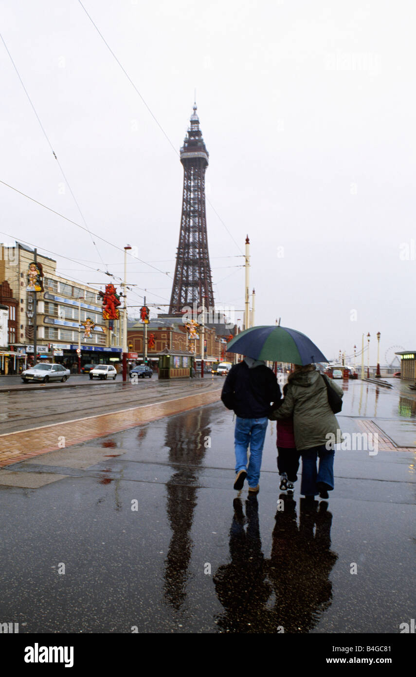 People walking beneath umbrella in the rain at Blackpool with Blackpool ...
