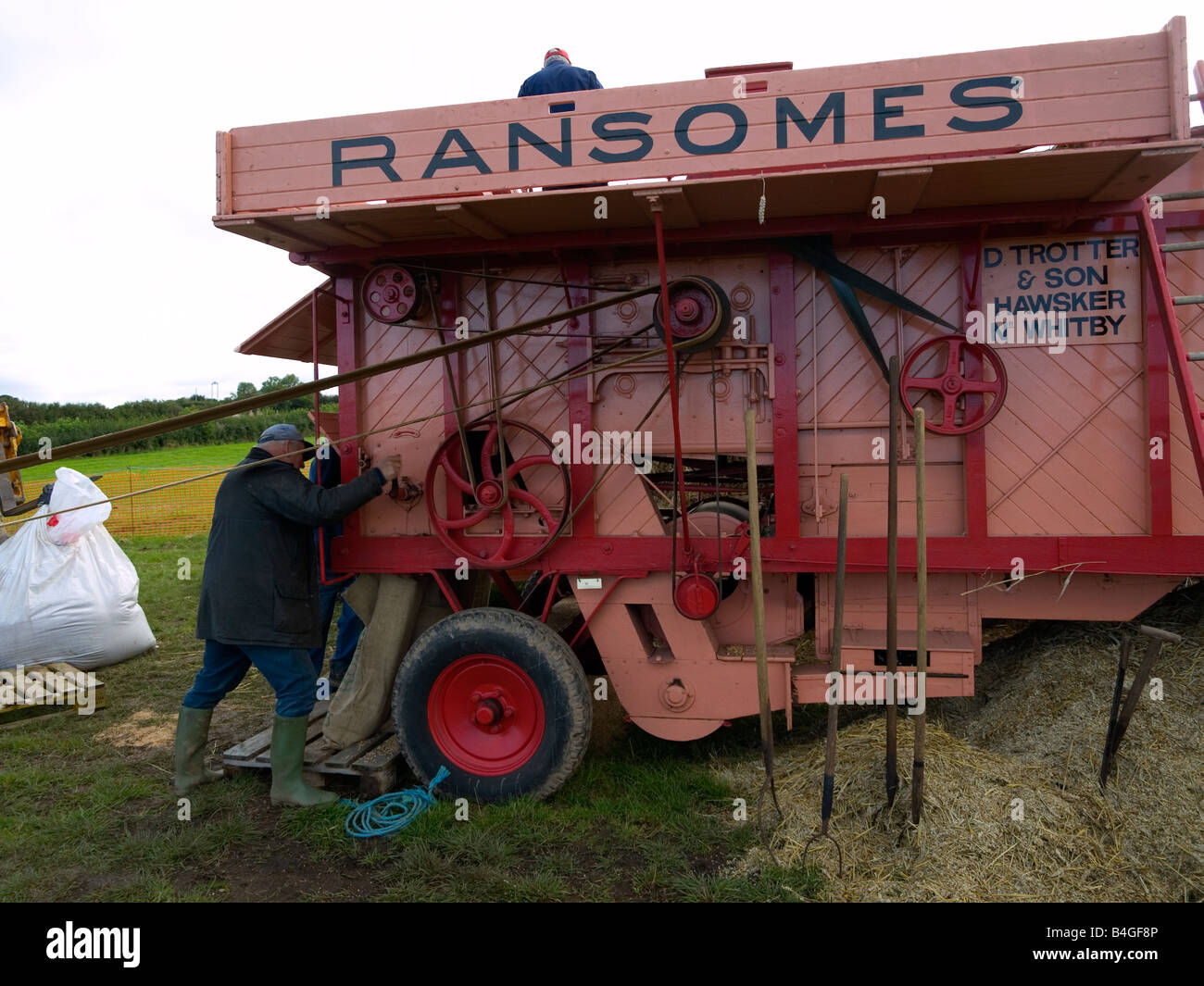 A farm worker using a threshing machine at a demonstration of vintage farm machinery North Yorkshire UK Stock Photo
